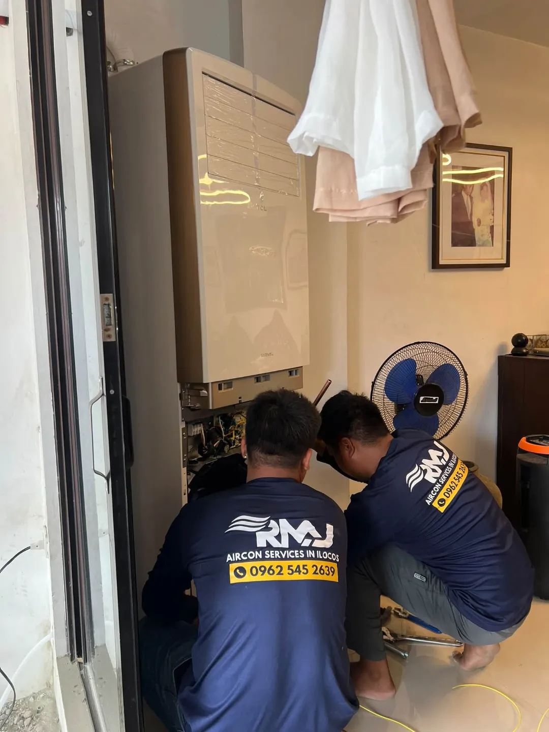 RMJ technicians servicing a floor-standing aircon unit
