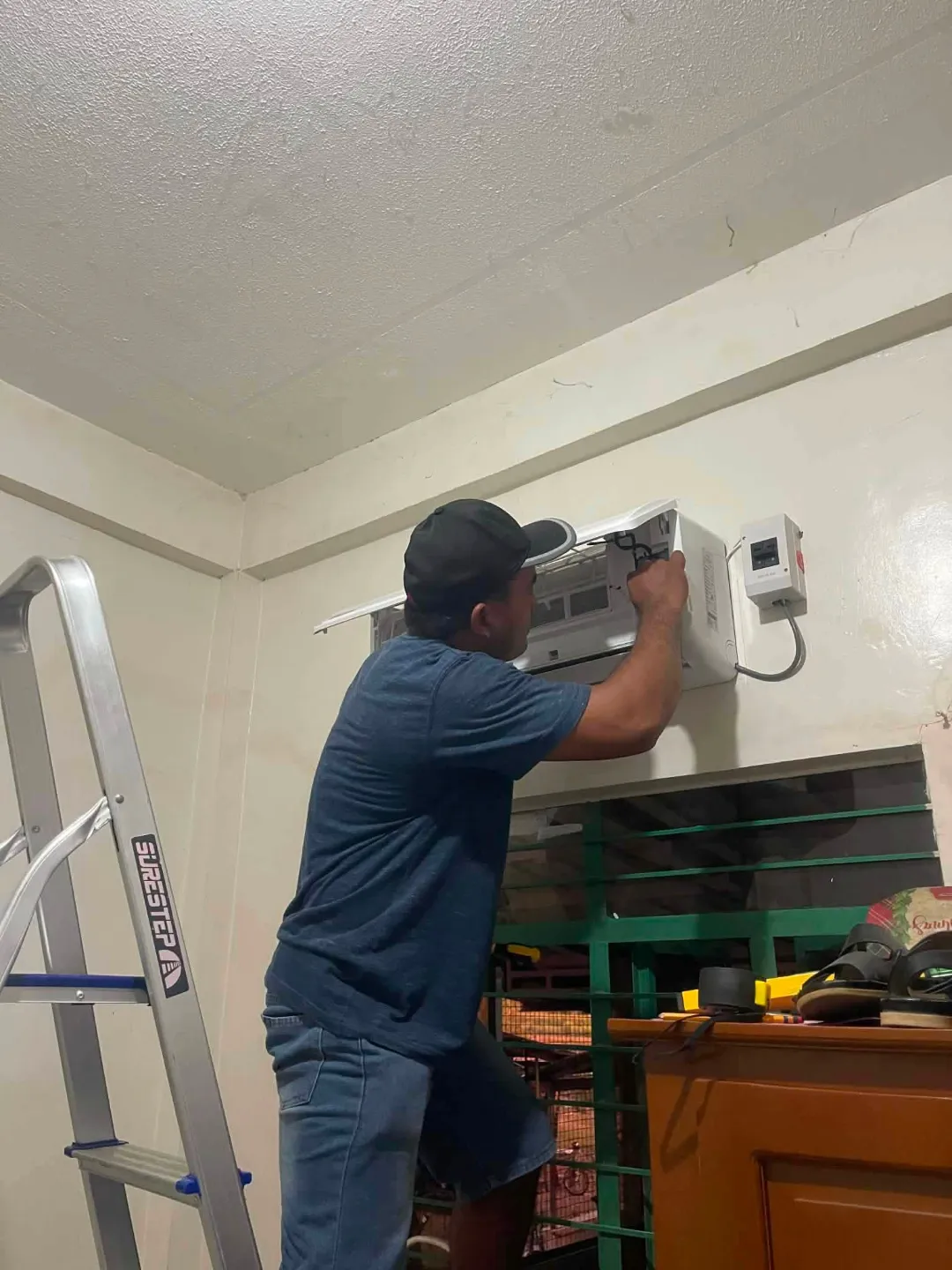 Technician servicing a wall-mounted indoor aircon unit
