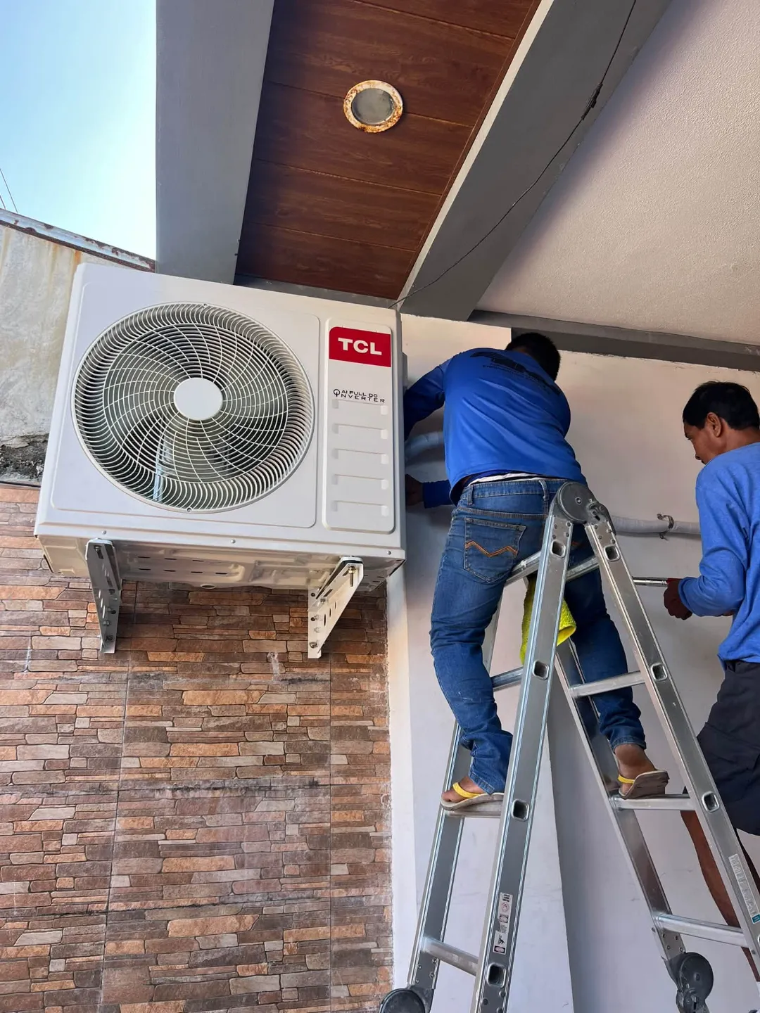 RMJ technicians installing an outdoor aircon unit beside a house